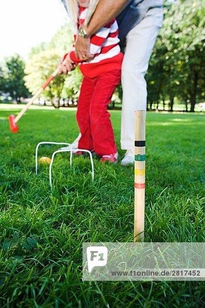 Girl and senior man playing croquet in the park Sweden.