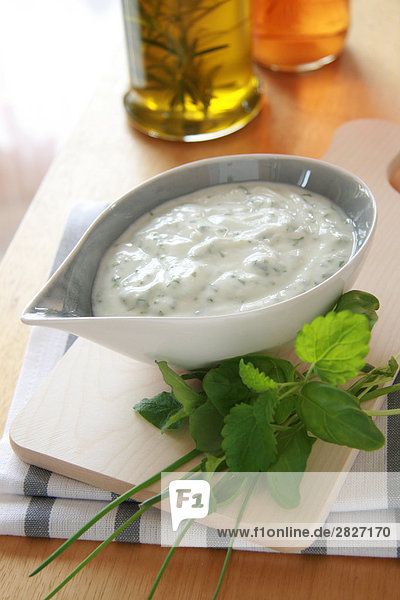 Close-up of bowl of cream cheese with herbs on cutting board
