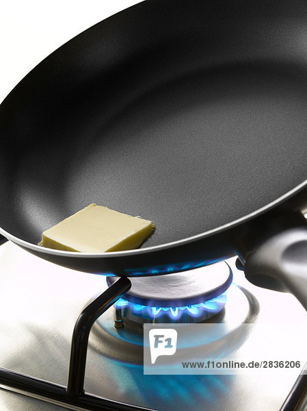 Stück Butter in einer Pfanne auf einem Gaskocher