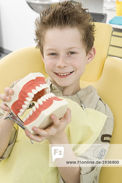 Portrait of boy holding denture