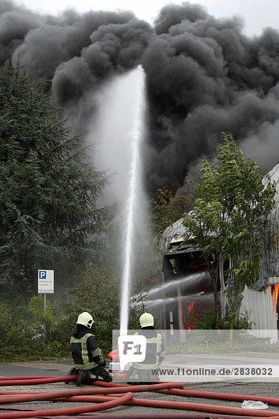 Two fire fighters extinguishing fire with hose  Huissen  Gelderland  Netherlands