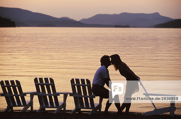 Junges paar kiss am Strand  im Lac Tremblant bei Sonnenuntergang am Mont Tremblant Resort  nördlich von Montreal  Québec  Kanada.