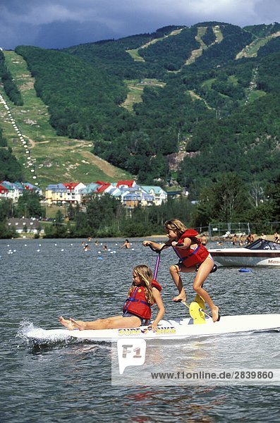 Zwei junge Mädchen spielen auf Surf-Bike' am Lac Tremblant  Mont Tremblant Resort  nördlich von Montreal  Québec  Kanada.