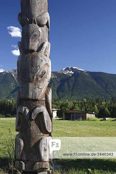 Totem pole and mountains at Kitwanga  British Columbia  Canada.