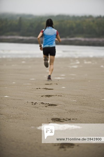 A young female running along the shores of the beach at Mispec Park  Saint John  New Brunswick  Canada.
