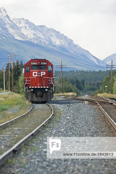 A CP Rail locomotive sits on the tracks with Mount Rundle in the background near Canmore Alberta  Canada.