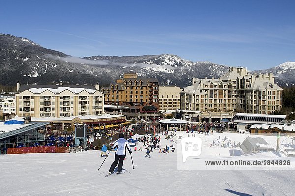 Skiers on slope with Whistler Resort in the background  Whistler  British Columbia  Canada