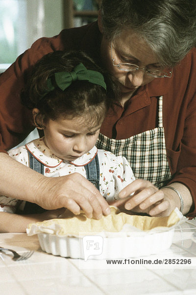 Großmutter bei der Zubereitung der Kuchenkruste mit Enkelin