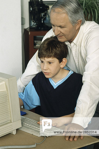 Grandfather and grandson using computer together