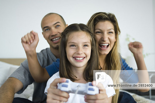 Mädchen beim Videospiel  Eltern beim Zuschauen und Anfeuern