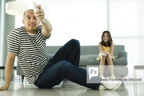 Vater und Tochter spielen Videospiel mit drahtlosen Controllern