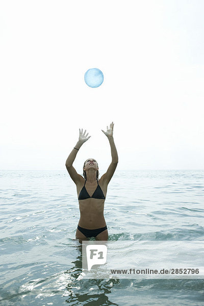 Teenager-Mädchen im Meer stehend  Ball fangend