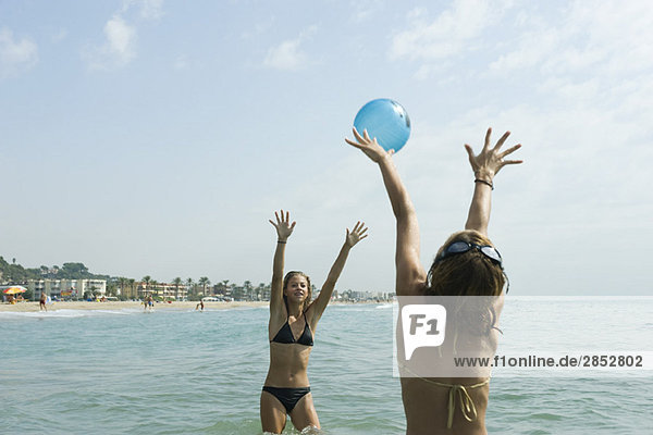 Teenagermädchen spielen mit Strandball im Meer