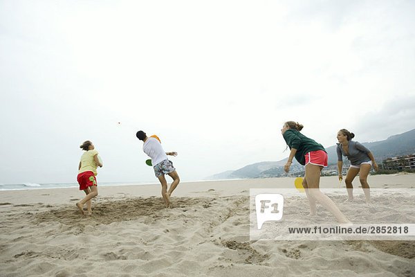 Teenager-Freunde spielen Paddleball am Strand