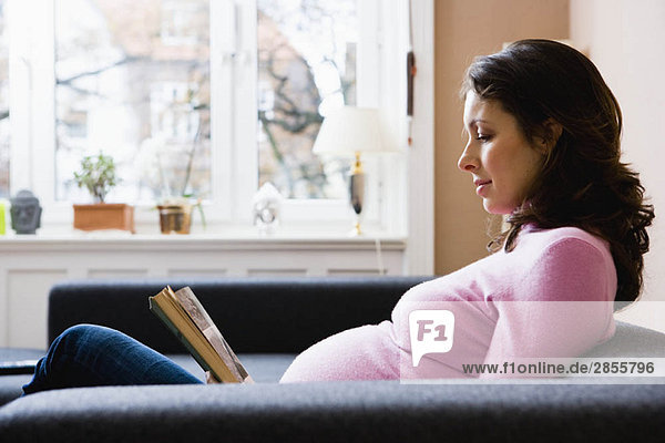 Schwangere Frau beim Lesen eines Buches