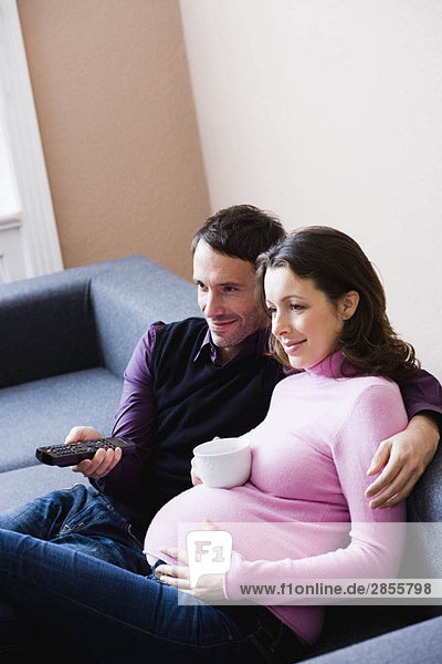 Pregnant woman and man sitting on couch