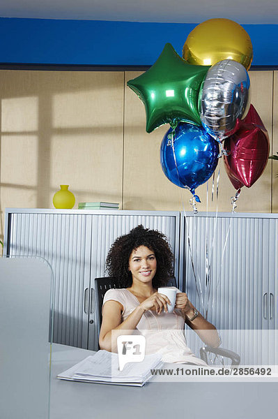 Junge Frau mit Ballons im Büro