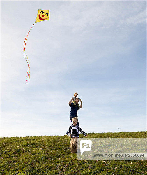 Zwei Jungen und Vater fliegen einen Drachen