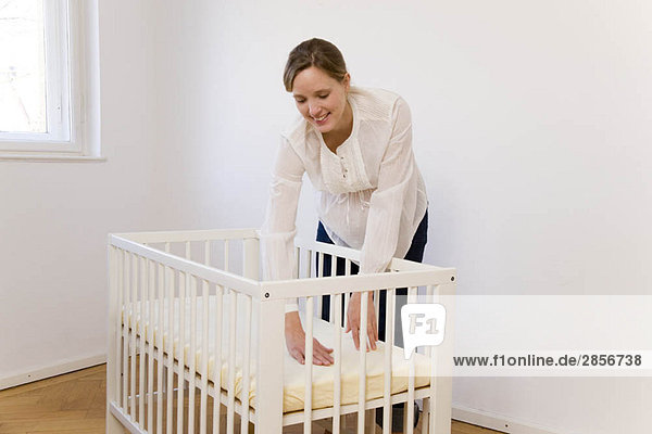 Pregnant woman putting together baby bed