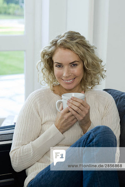 Frau auf Sofa mit Tasse/Tasse
