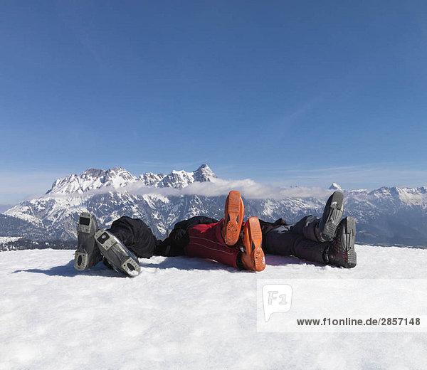 3 Männer liegen im Schnee auf dem Gipfel des Berges