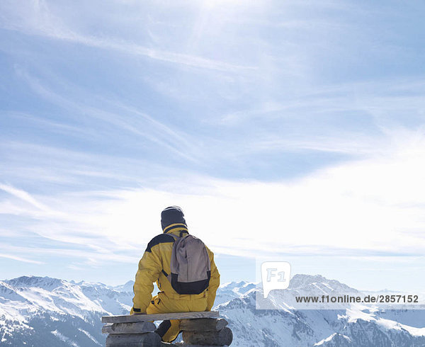 Mann auf der Bank auf dem Berggipfel sitzend