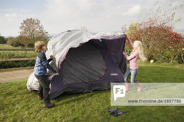 Junge und Mädchen bauen ein Zelt auf