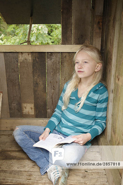 Junges Mädchen liest im Baumhaus
