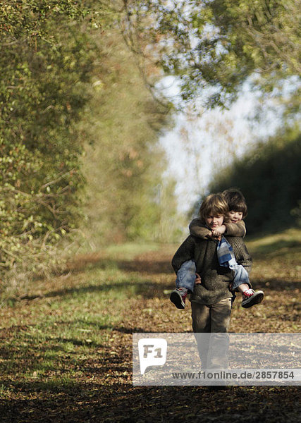 Boy carrying young child in countryside