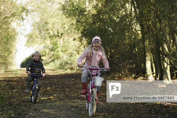 Boy and girl riding bikes in countryside