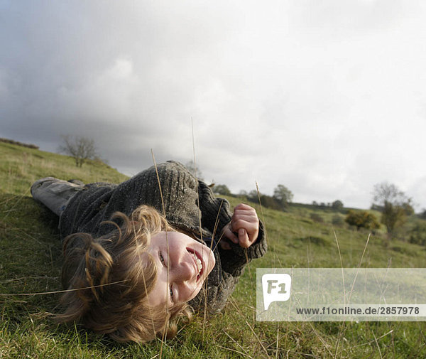 Junge auf Gras am Hang liegend