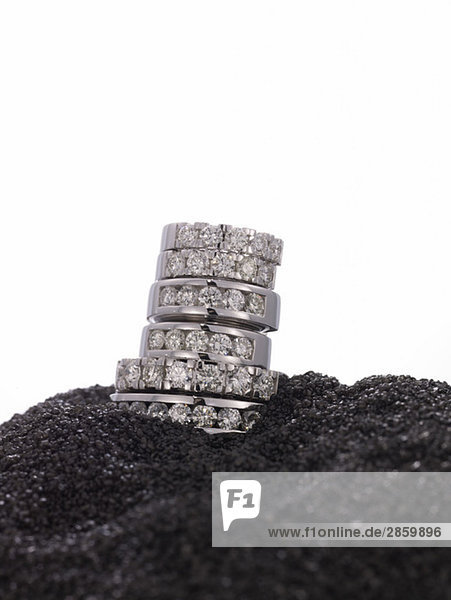 Gestapelte Diamantringe auf schwarzem Sand