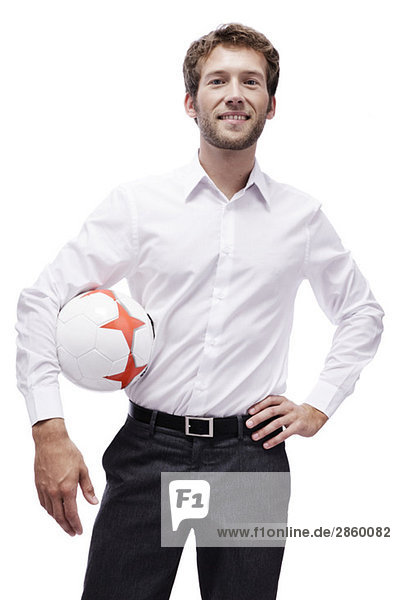Junger Mann hält Fußball,  lächelnd,  Porträt