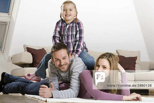 Parents and daughter (3-4)  relaxing at home
