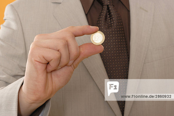 Man holding Euro coin  middle section  close up