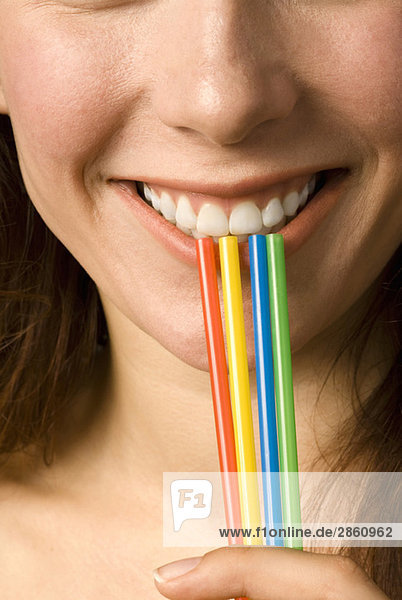 Young woman holding four straws  smiling  close up