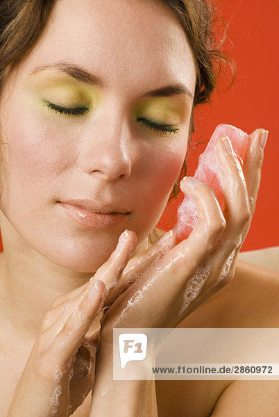 Young woman holding cake of soap  eyes closed  close up