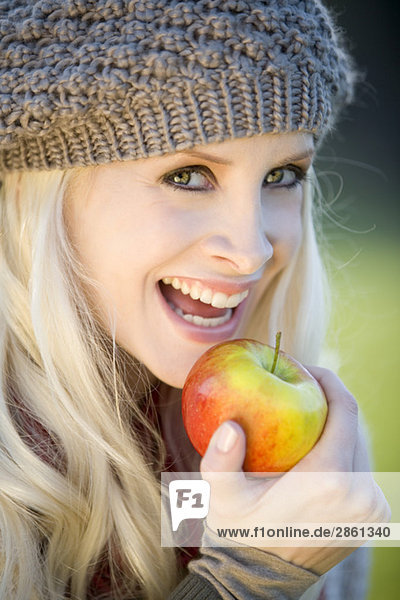 Junge Frau hält einen Apfel  lächelnd  Portrait  Close-uo