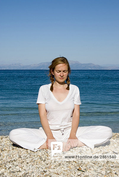 Greece  Ithaca  Woman exercising yoga on beach