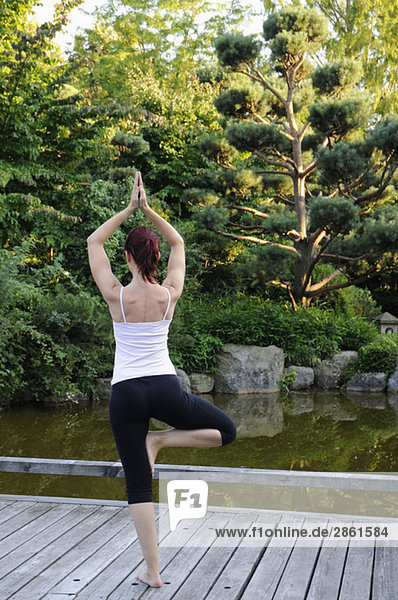 Young woman exercising yoga rear view