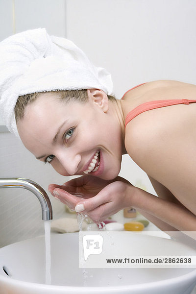 Junge Frau wäscht Gesicht  lächelnd  Portrait