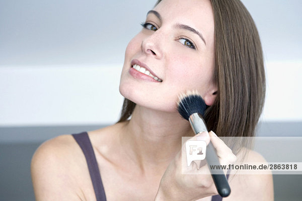 Young woman using make-up brush  portrait  close up
