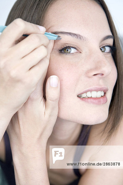 Young woman plucking her eyebrows  portrait  close-up
