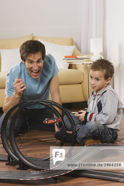 Vater und Sohn (4-5) spielen mit der Spielzeug-Rennbahn