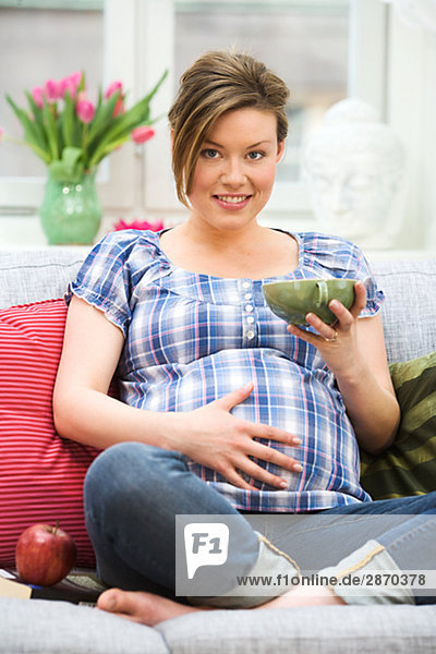 A pregnant woman sitting in a couch Sweden.