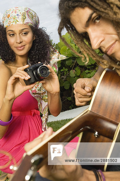Frau macht ein Foto von einem Mann  der Gitarre spielt.