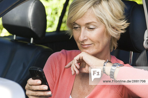 Woman sitting in a car and text messaging