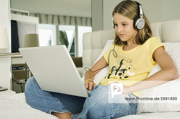 Girl working on a laptop and listening to headphones