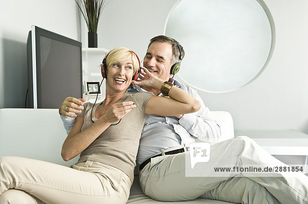 Couple listening to music with headphones and smiling