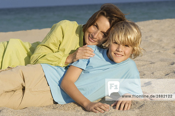 Frau liegt mit ihrem Enkel am Strand.